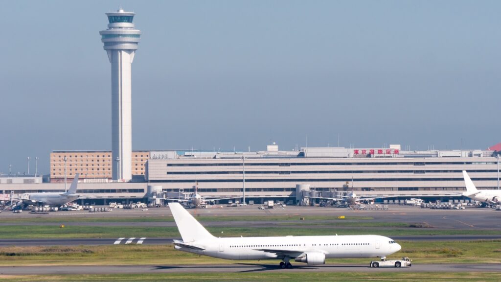 空港の滑走路を走る旅客機と管制塔